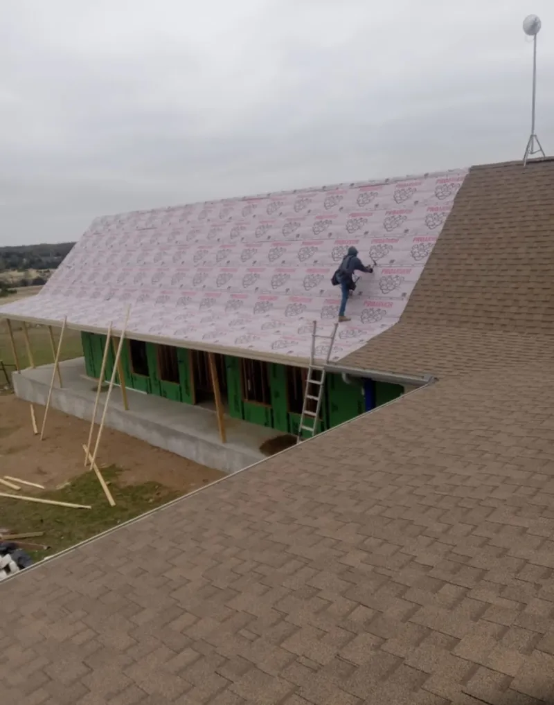 Worker preparing underlayment for a metal roof installation in Cannon